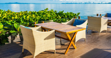 Light-toned wooden furniture in a bright summer living space featuring a cozy rocking chair, slatted bench, and natural wood coffee table under soft sunlight.